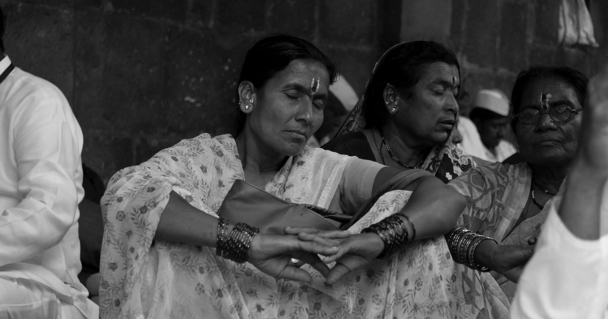 Women in traditional attire meditating at a religious gathering in Pune, India.