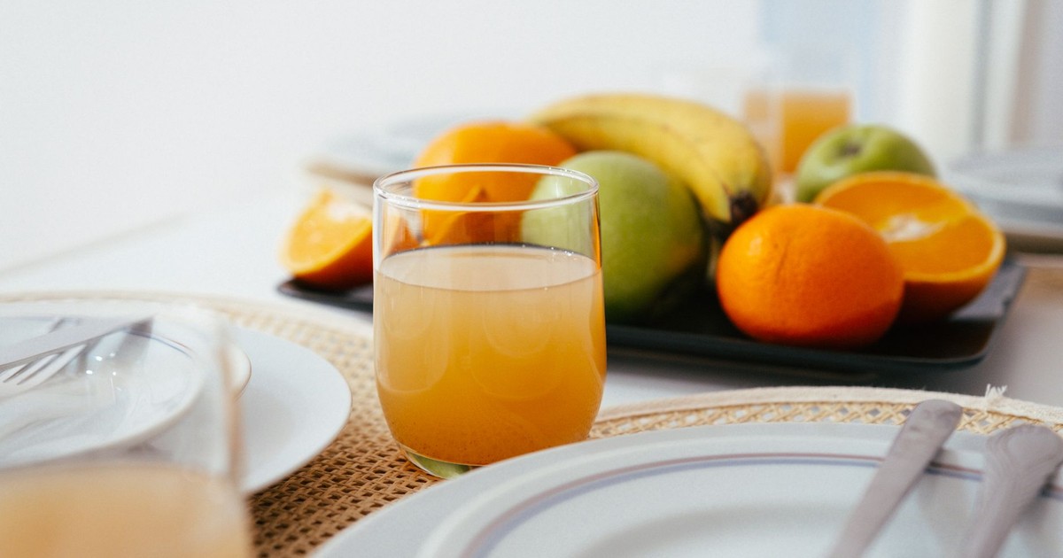 Bright and fresh breakfast setup featuring orange juice and a variety of fruits on a neatly arranged table.