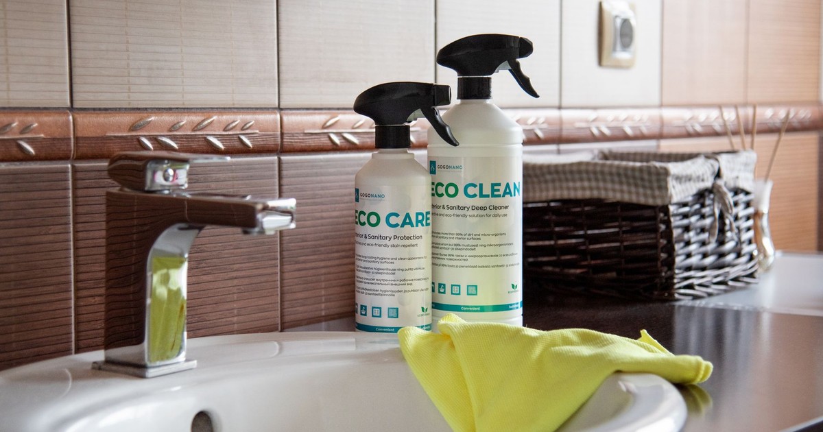 Eco-friendly cleaning products displayed on a bathroom sink with tiles and a basket.