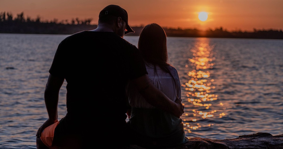 A couple shares a romantic embrace by the seaside during a stunning sunset, reflecting love and tranquility.