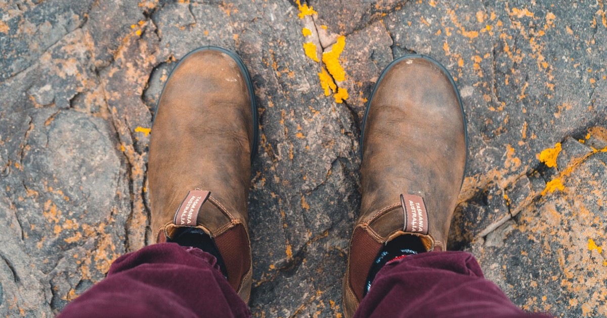 Close-up of brown leather boots standing on a textured stone path, showcasing rugged style.
