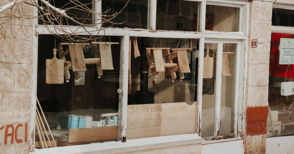 A rustic storefront showcasing wooden cutting boards and urban architecture. Ideal for vintage themes.