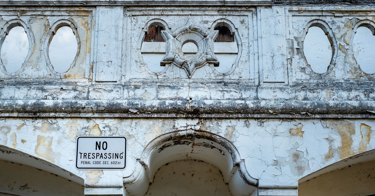 An old, peeling paint wall with a no trespassing sign, conveying urban decay.