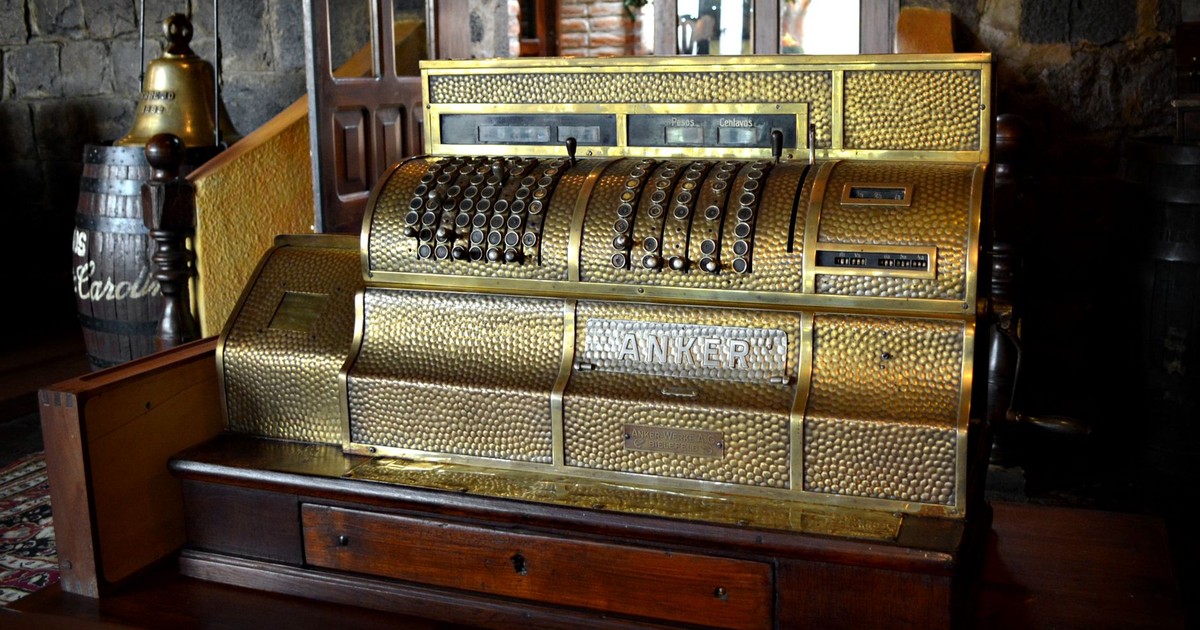 A beautifully preserved vintage brass cash register displayed in a rustic, wooden interior.