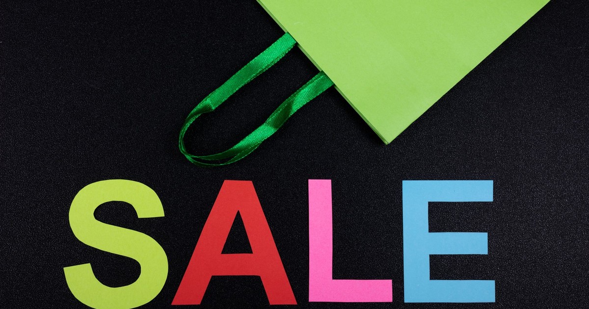 Bright sale text with green shopping bag on black background, perfect for promotions.