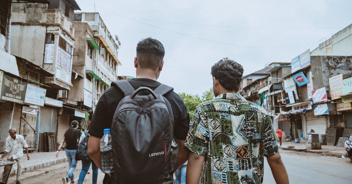 Two men walk through a lively urban street, showcasing diverse culture and city life.