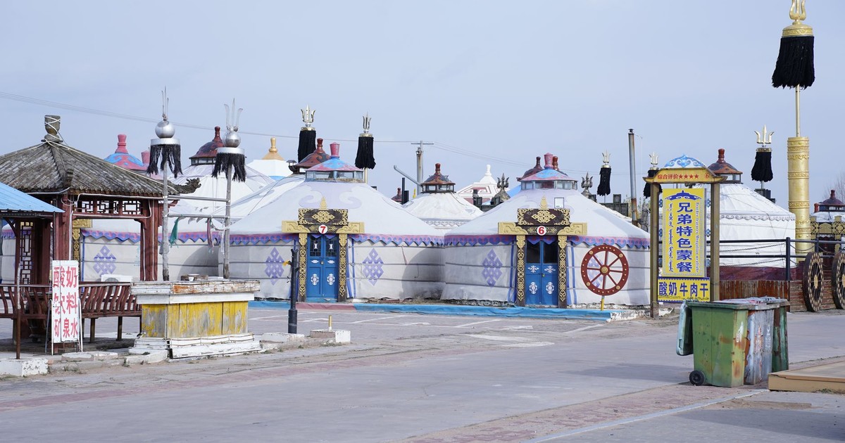 Colorful traditional Mongolian yurts in a cultural village under a clear blue sky.