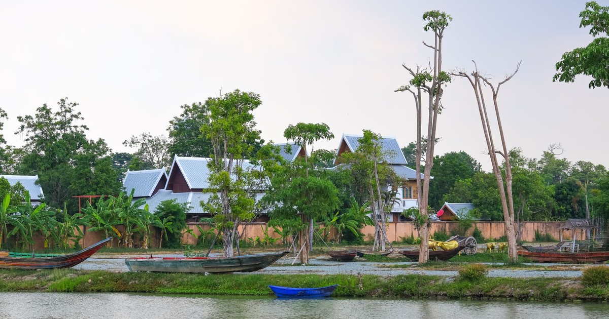 Serene riverside scene with traditional boats and lush greenery in Chonburi, Thailand.