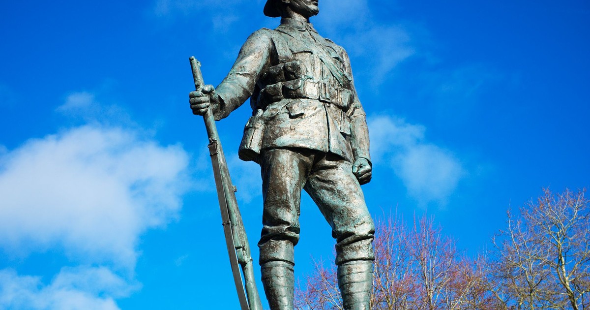 A striking bronze statue of a World War I soldier in Winchester against a bright blue sky.