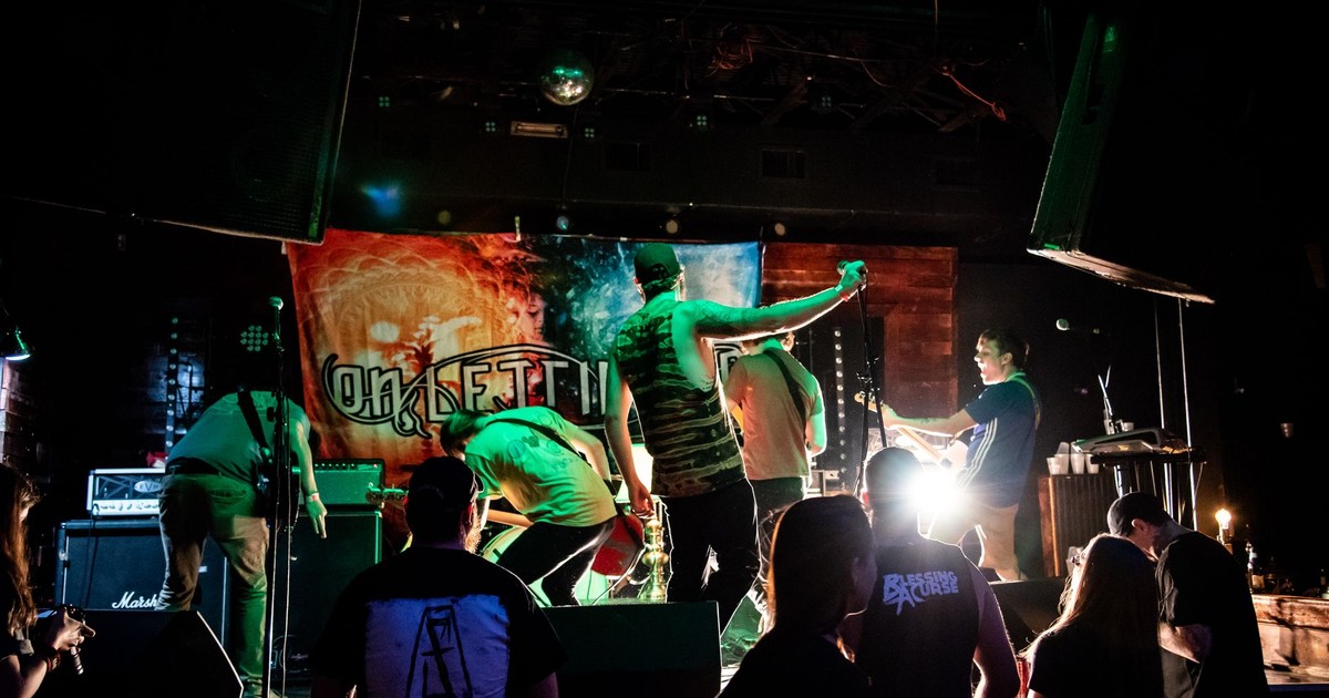 Energetic band performance on stage with vibrant lights and audience interaction.