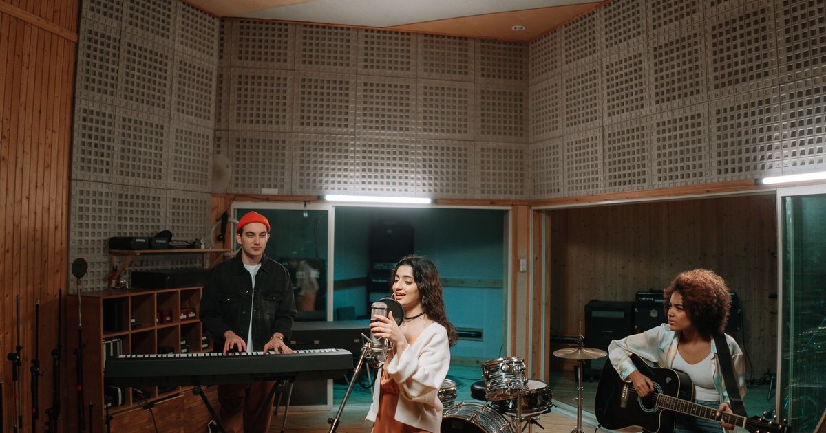 A diverse band practicing music in a professional recording studio setting.