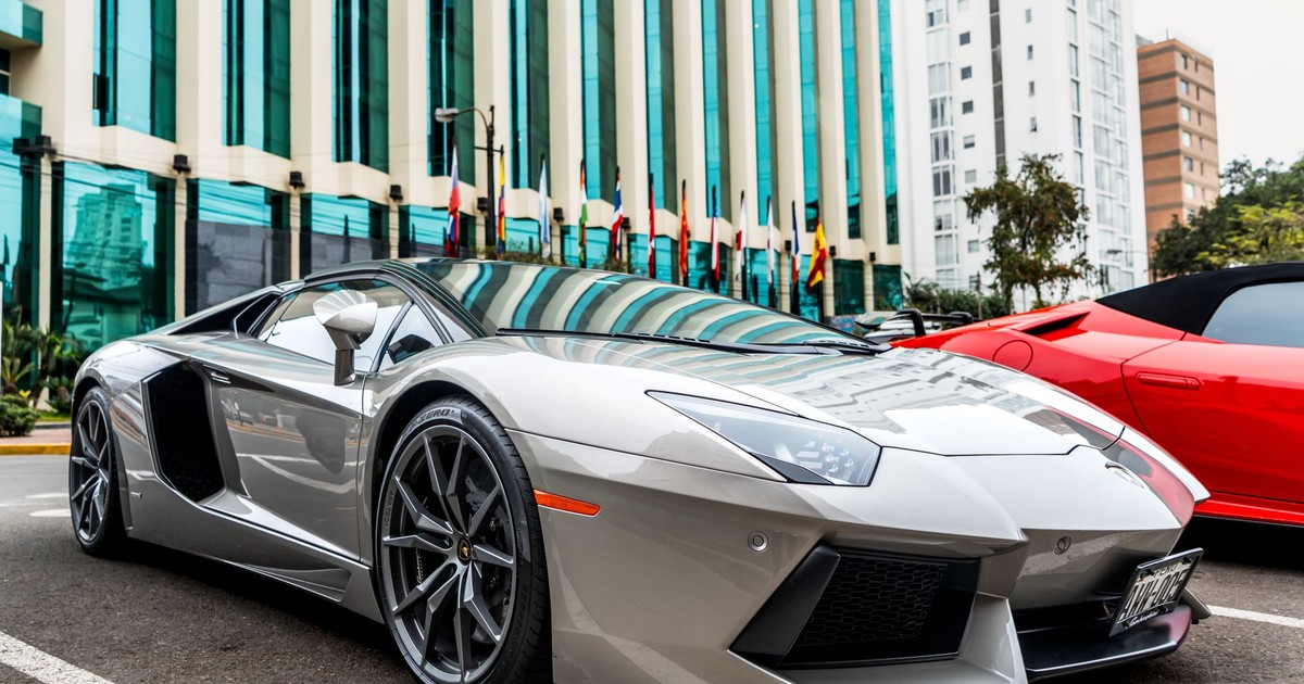 Luxury silver sports car parked in front of modern glass facade building.