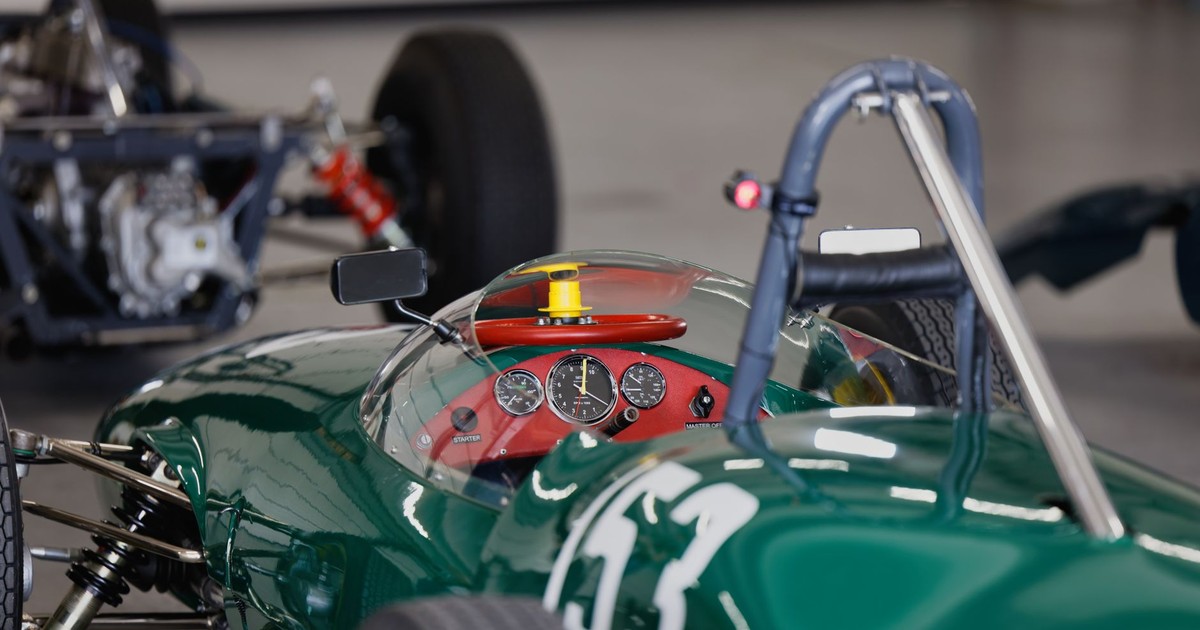 Detailed view of vintage green race car cockpit with dashboard instruments in garage.
