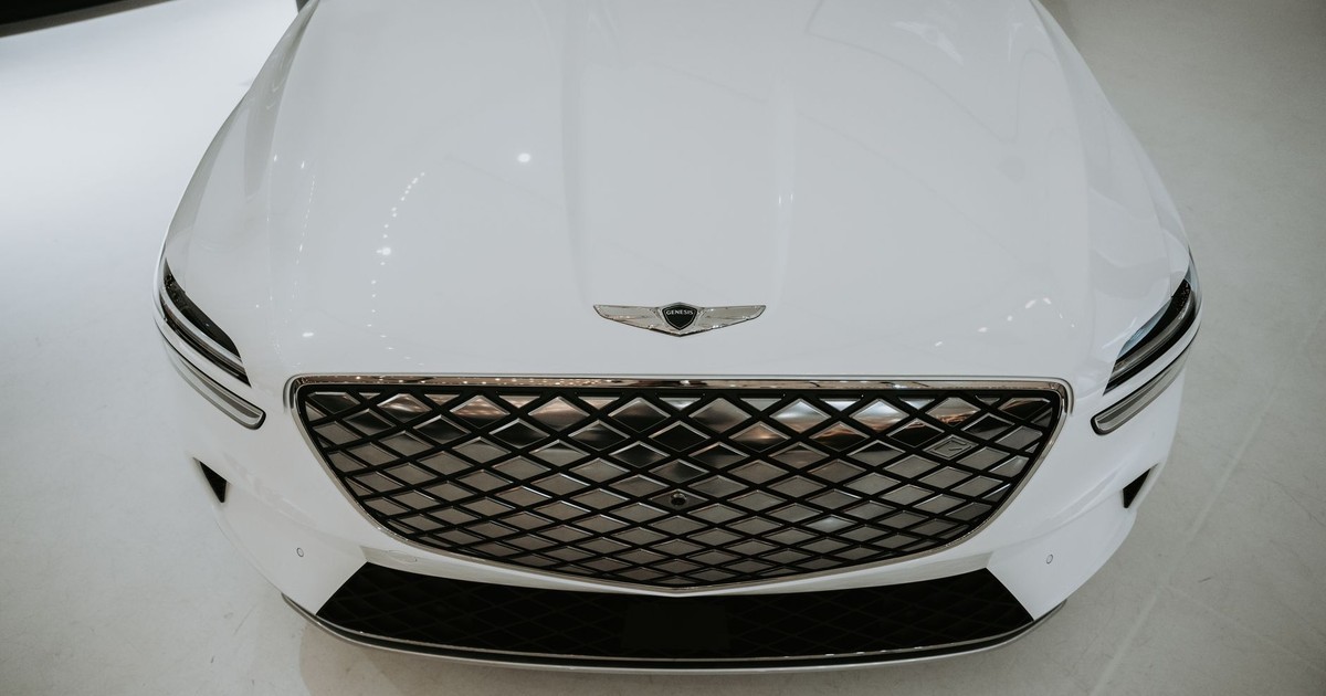 Close-up of a luxury white car showcasing its front grille in a modern showroom.
