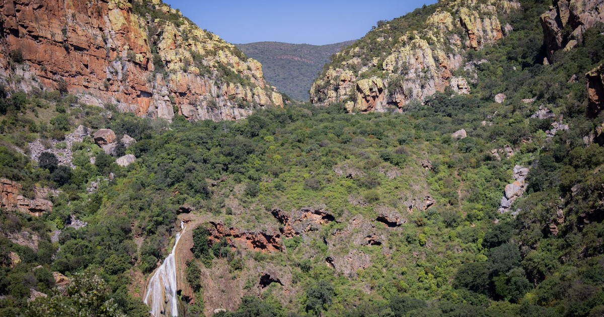 Beautiful waterfall cascading through a lush green valley surrounded by rocky cliffs.