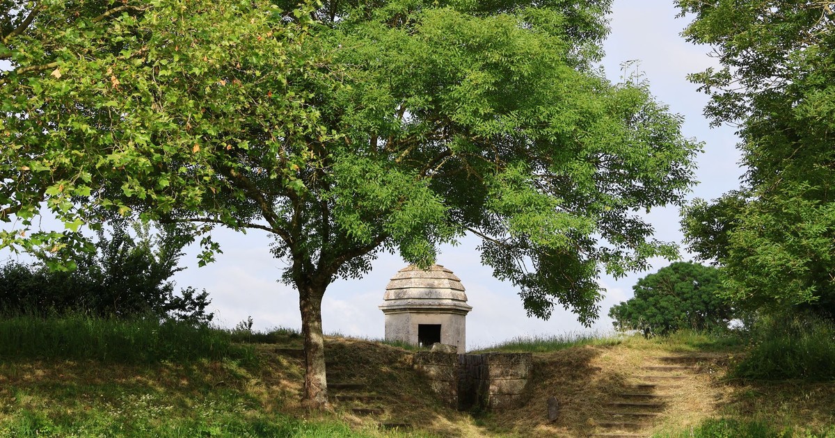 Historic stone structure surrounded by vibrant green trees and grass.
