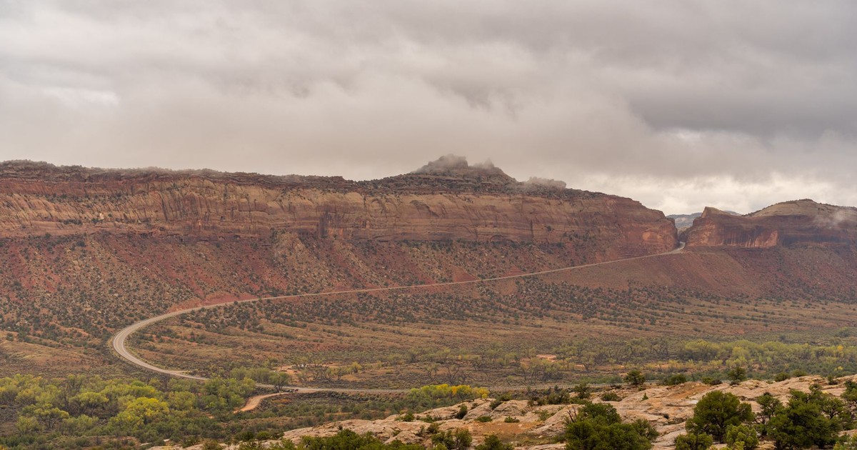 Majestic Utah canyon with winding road under a dramatic cloudy sky, perfect for adventure travel.