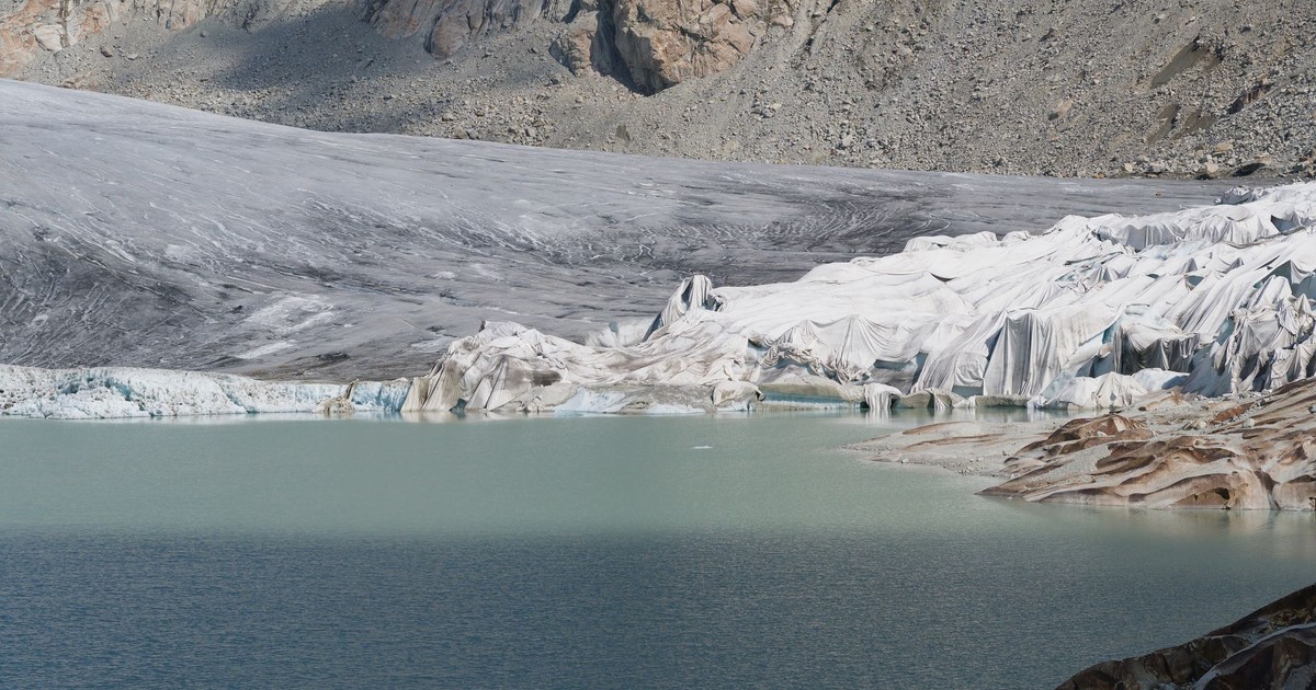 Breathtaking view of a Swiss glacier surrounded by mountains and a serene blue lake, capturing nature's raw beauty.