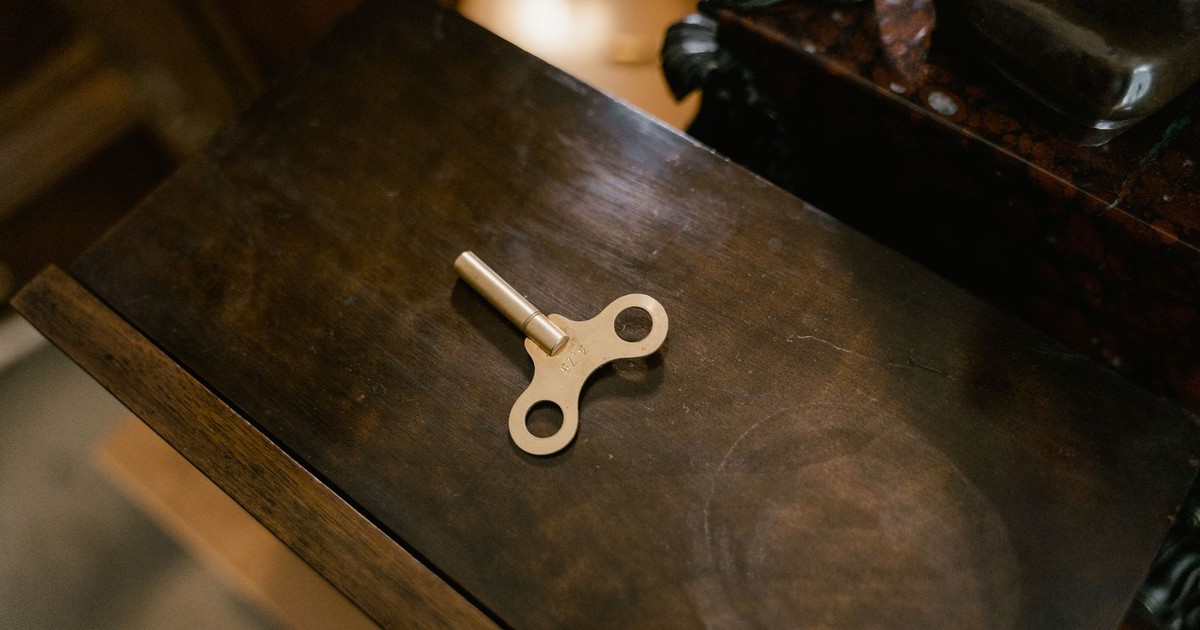 A vintage clockwork key placed on a polished wooden surface, showcasing retro charm.