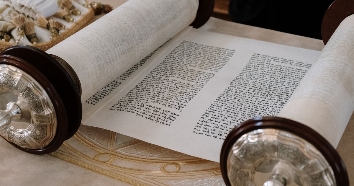 A close-up view of an open Sefer Torah on a synagogue table, highlighting intricate details.