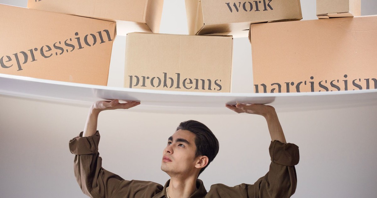 Young man struggles with metaphorical burdens symbolized by labeled boxes suspended above him.