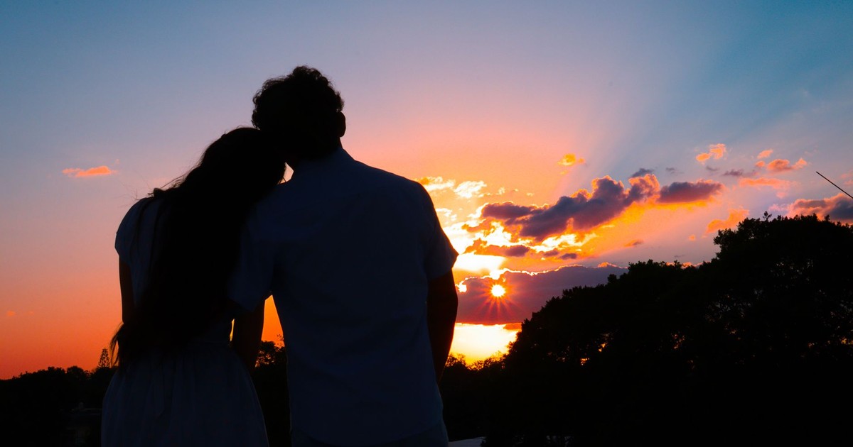 Silhouetted couple embracing at sunset, creating a romantic and serene atmosphere.