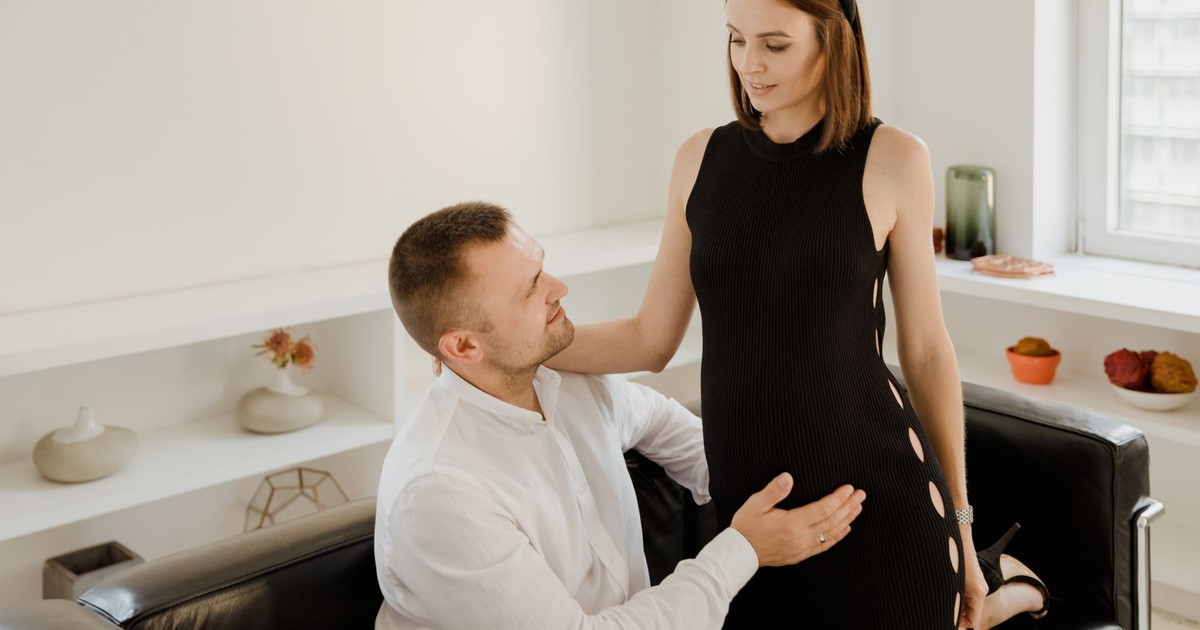 A couple lovingly embraces pregnancy in a modern, serene indoor setting.