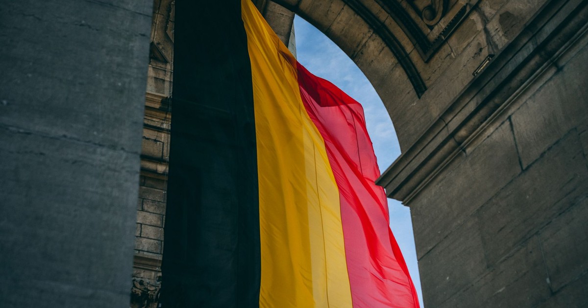 Vibrant Belgian flag under iconic archway in Brussels, symbolizing national pride.
