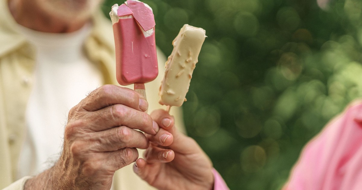 Close-up of elderly couple holding colorful ice pops outdoors, sharing a sweet moment.