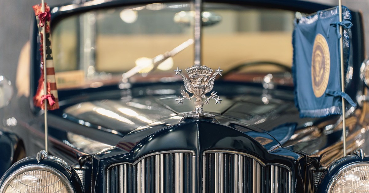 Close-up of a vintage ceremonial car with presidential emblem and flags displayed prominently.