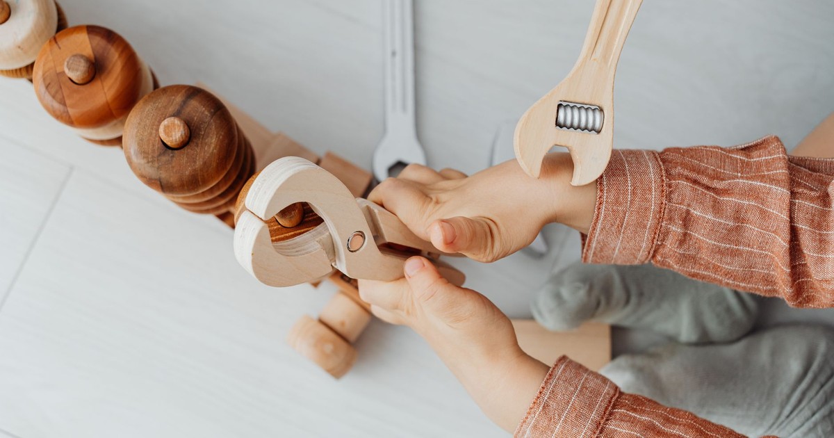 Close-up of a child playing with wooden toy tools, enhancing creativity and motor skills.