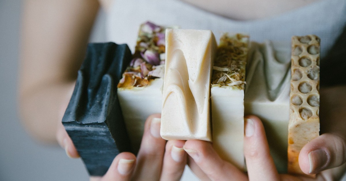 A variety of handcrafted organic soaps held in hands, showcasing natural ingredients and textures.