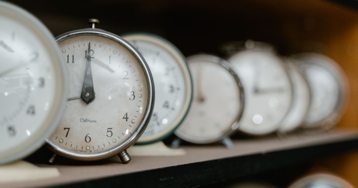 A collection of vintage analogue alarm clocks arranged on a wooden shelf.
