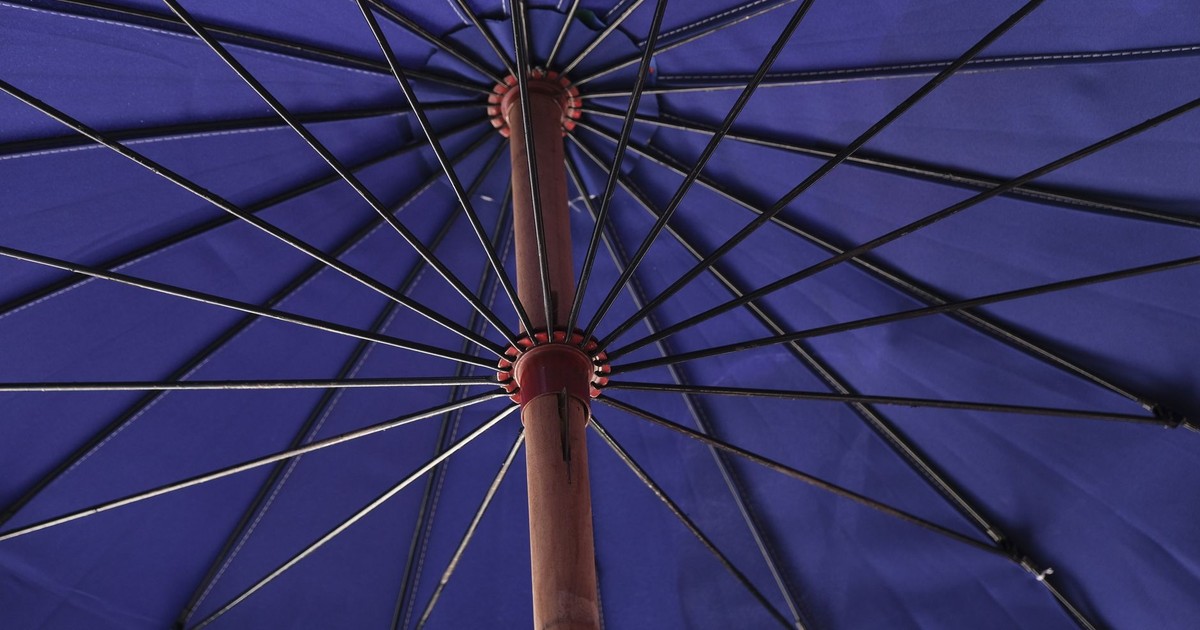 Detailed view of a blue umbrella from below, showing metal spokes and wooden handle.