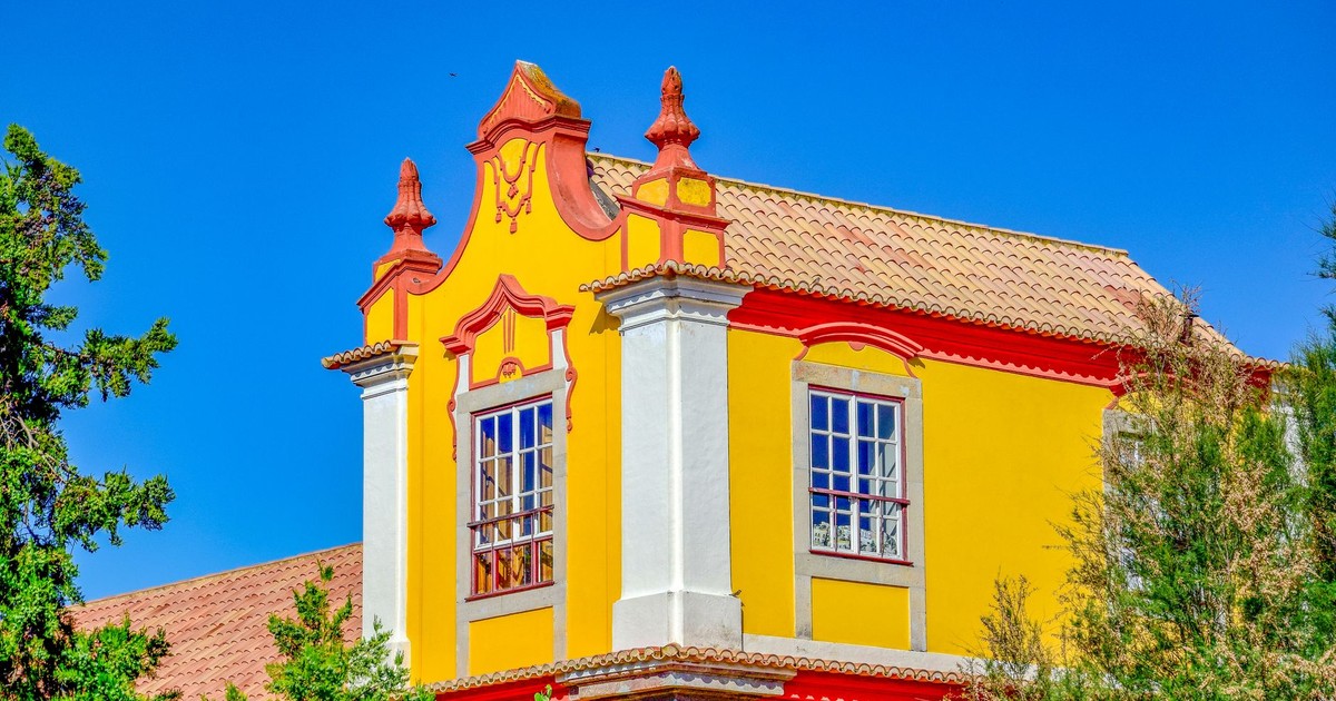 Vibrant yellow historic building facade in Tavira, Portugal, under a clear blue sky.