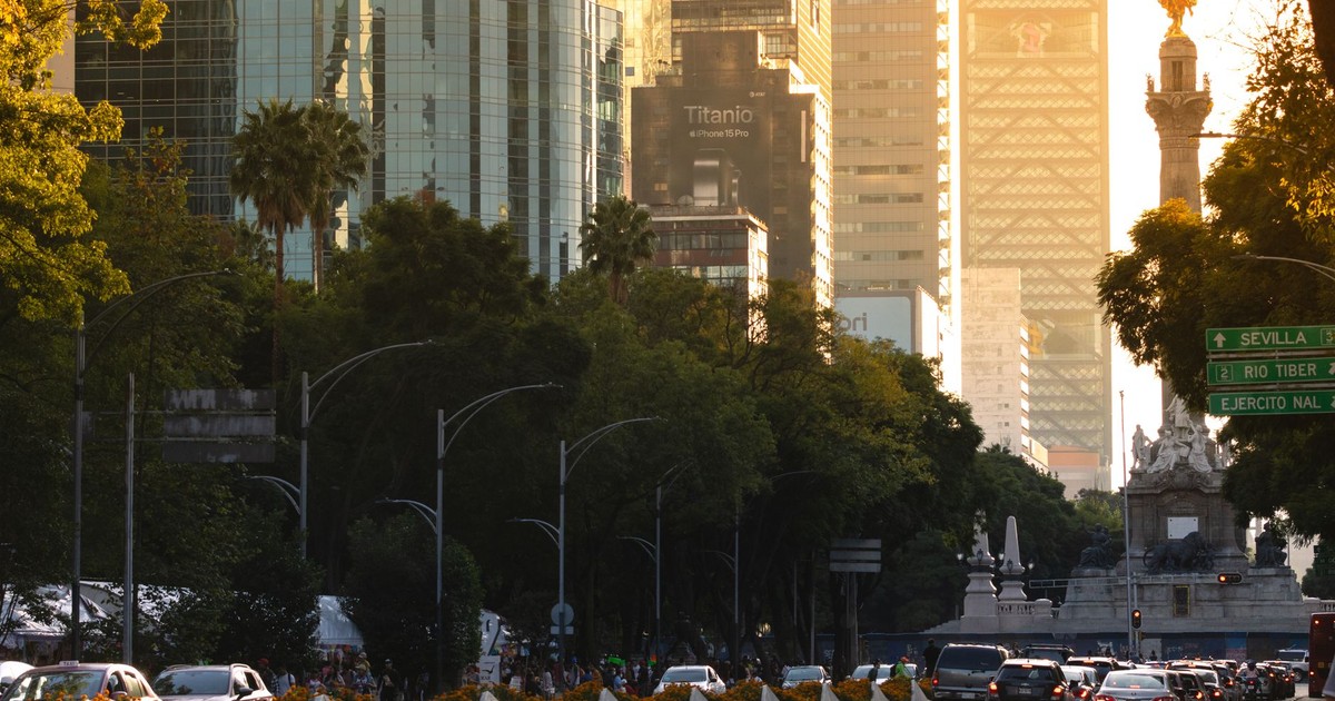 Urban scene of Ciudad de México with iconic Angel of Independence and skyscrapers at sunset.