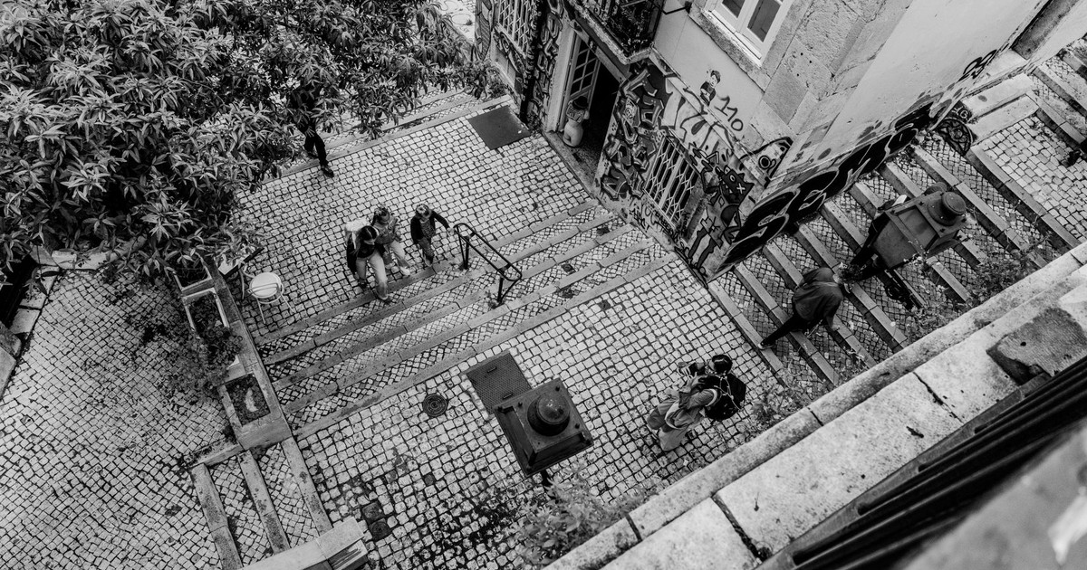 Black and white aerial photo capturing people on cobblestone steps with graffiti.