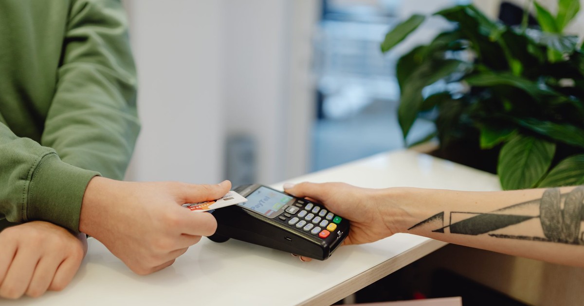 A close-up view of a contactless payment being made with a bank card over a payment terminal.