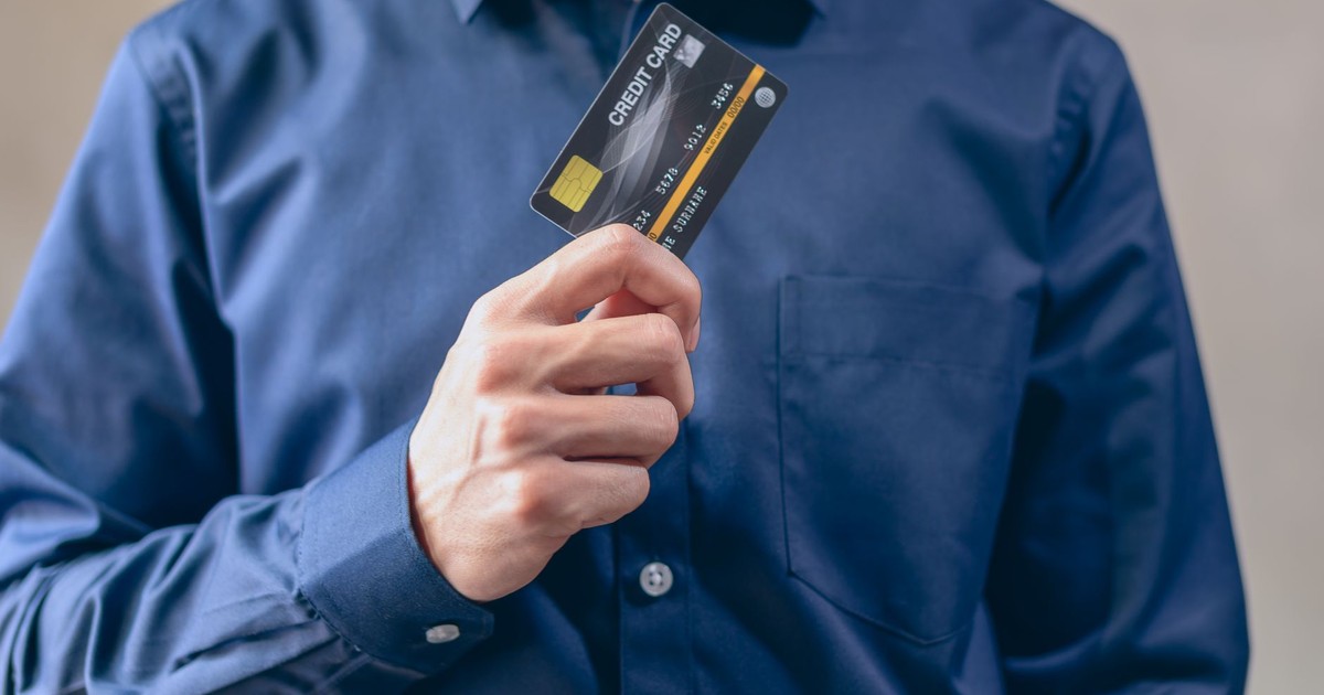 Close-up of a man in a blue shirt holding a credit card, symbolizing finance and security.