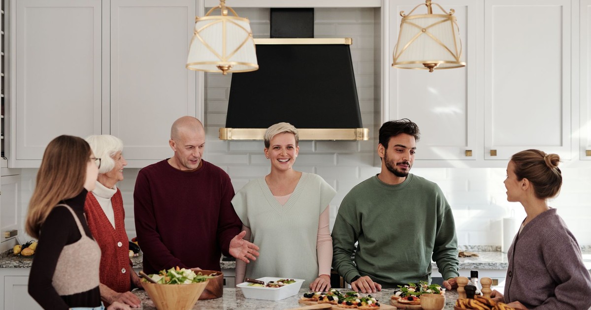 A multi-generational family enjoying a meal preparation together in a bright kitchen.