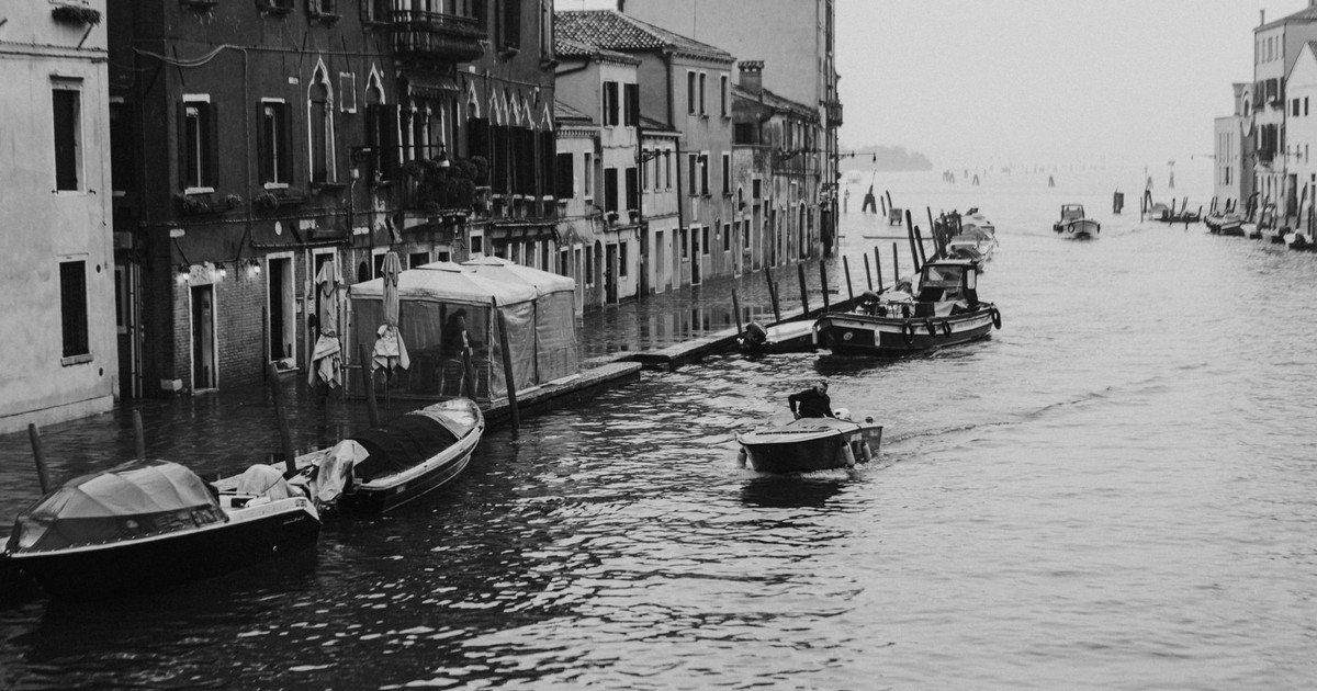 Elegant black and white photo of Venice canals, showcasing gondolas and historic architecture.