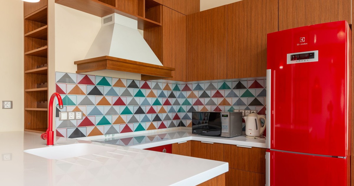 Contemporary kitchen design featuring colorful geometric tiles and red appliances.