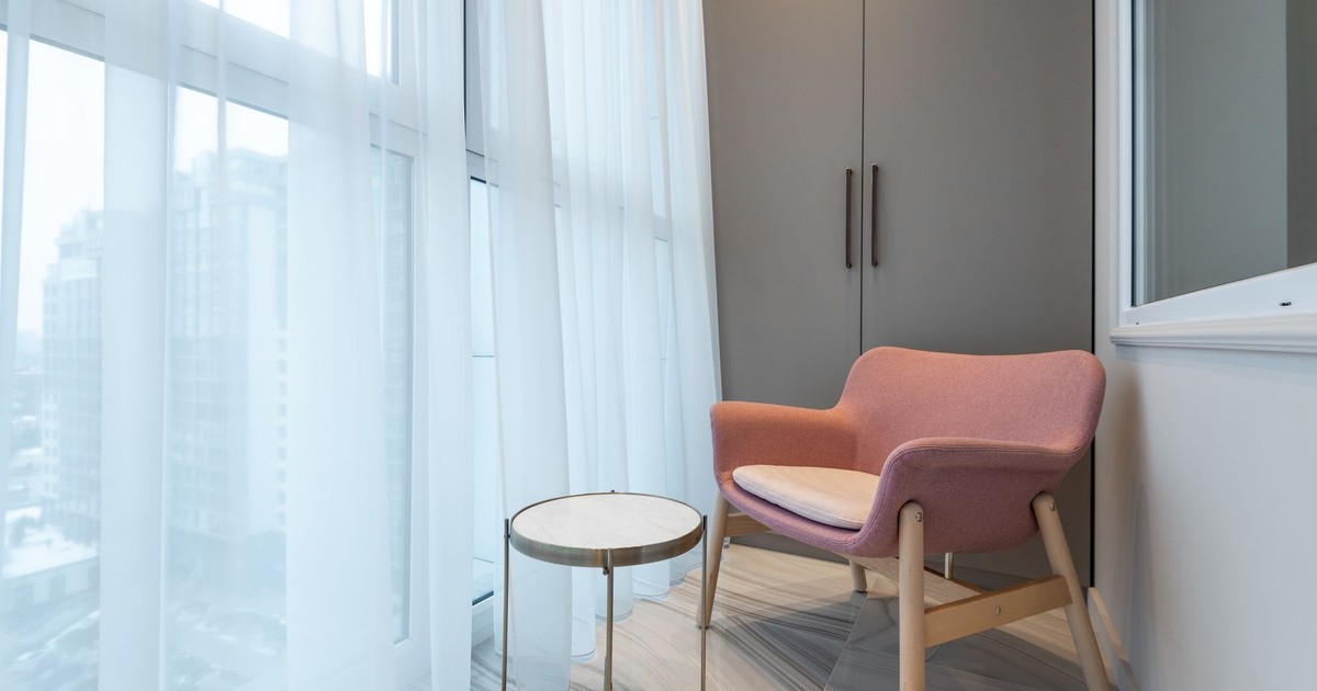Creative design of balcony with table and armchair on floor against curtain in contemporary apartment