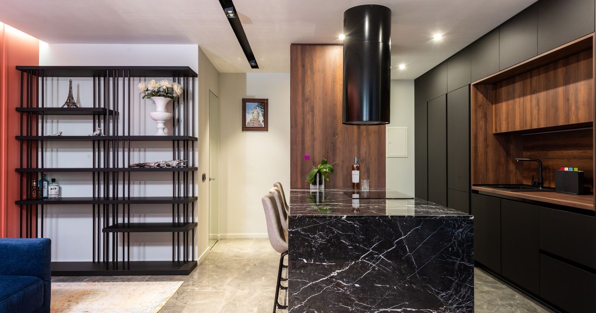 Modern kitchen interior with black marble island and wooden cabinets, featuring a sleek design.