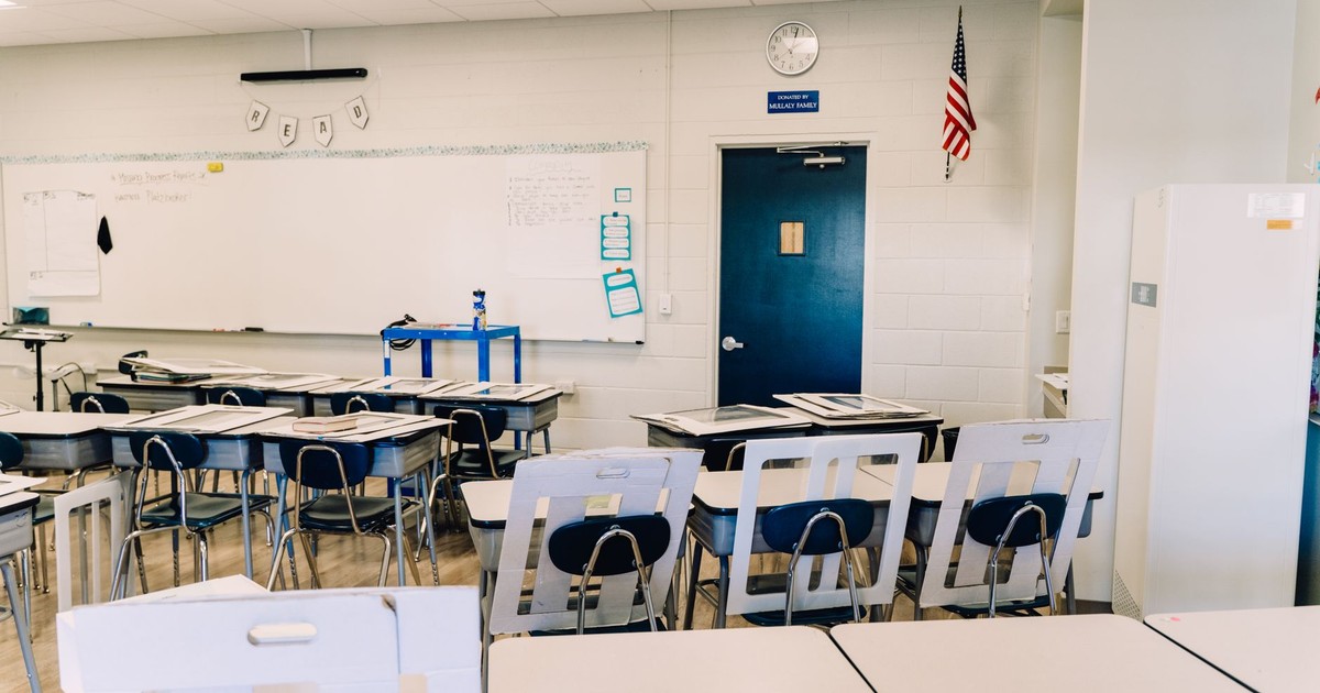 Bright empty classroom featuring desks, a whiteboard, and an American flag. Ideal learning environment.