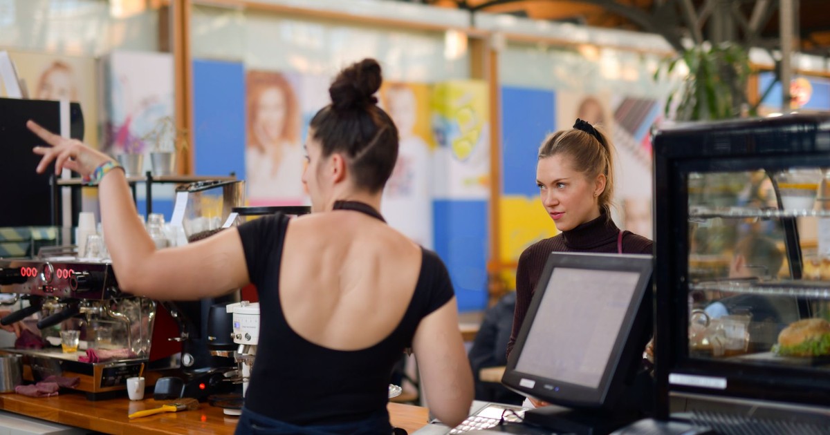 Two women interacting at a café counter, showcasing vibrant atmosphere and customer service.