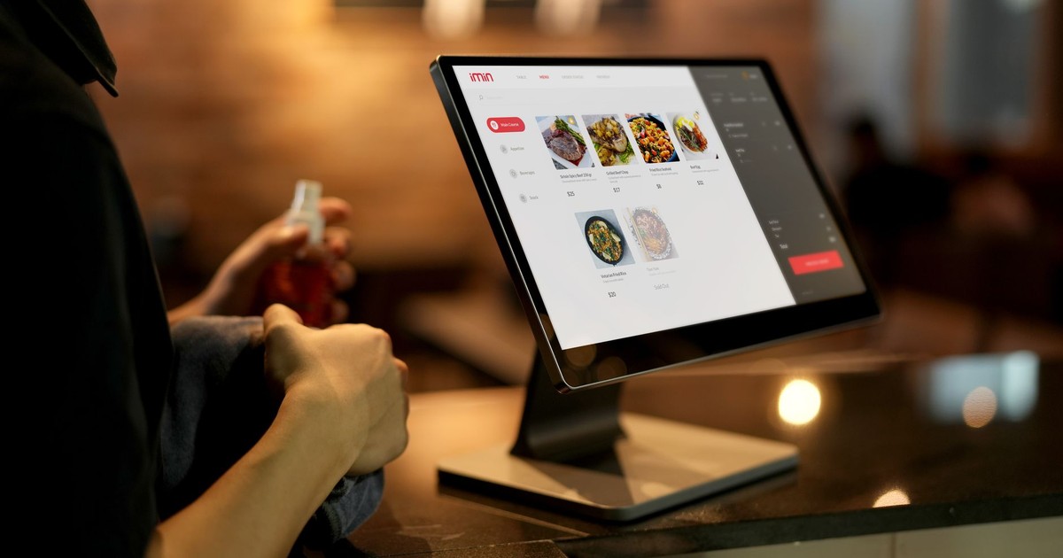A person using a touchscreen ordering system in a modern restaurant setting.