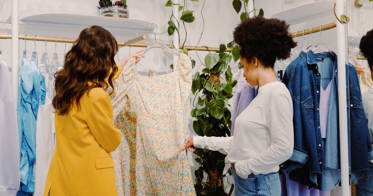 Two women shopping for stylish clothing in a trendy boutique, focused on a floral summer dress.