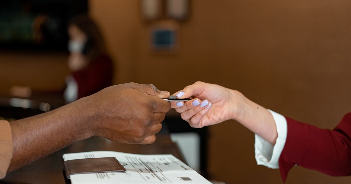 Close-up of a hotel receptionist receiving a credit card from a guest, highlighting a transaction at check-in.