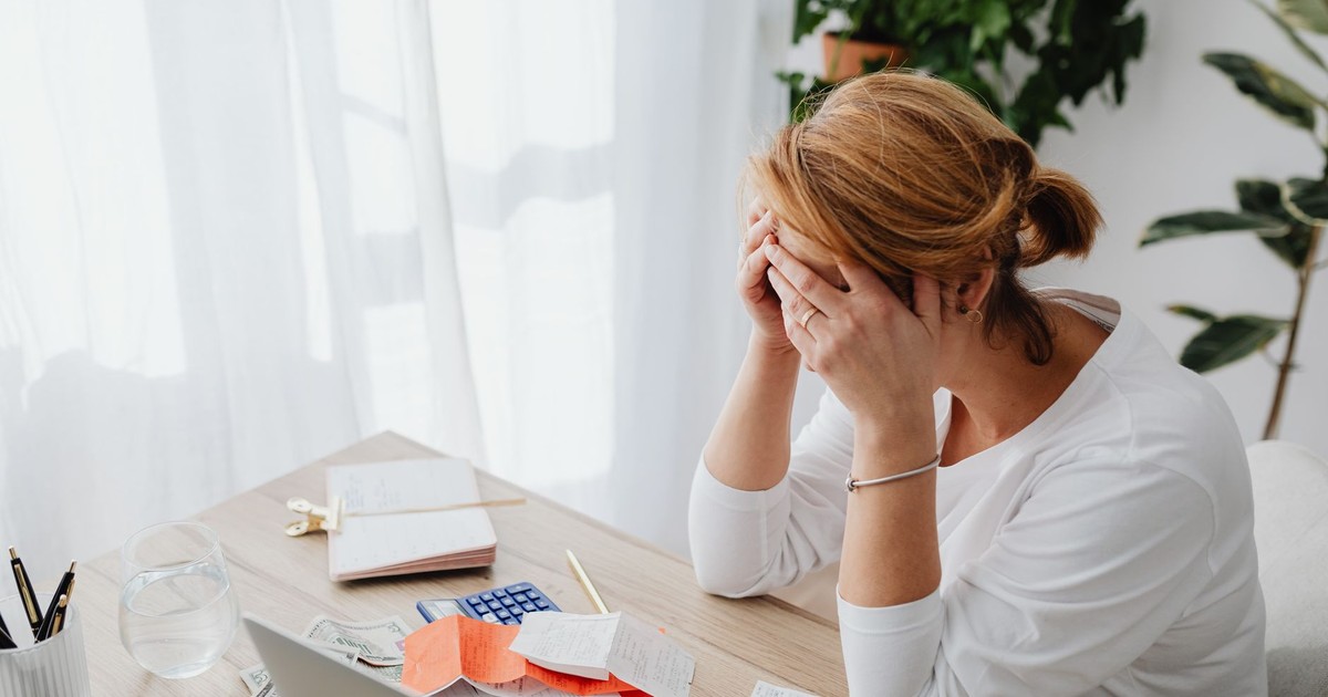 Woman stressed over financial receipts at a desk, dealing with expenses and calculations.